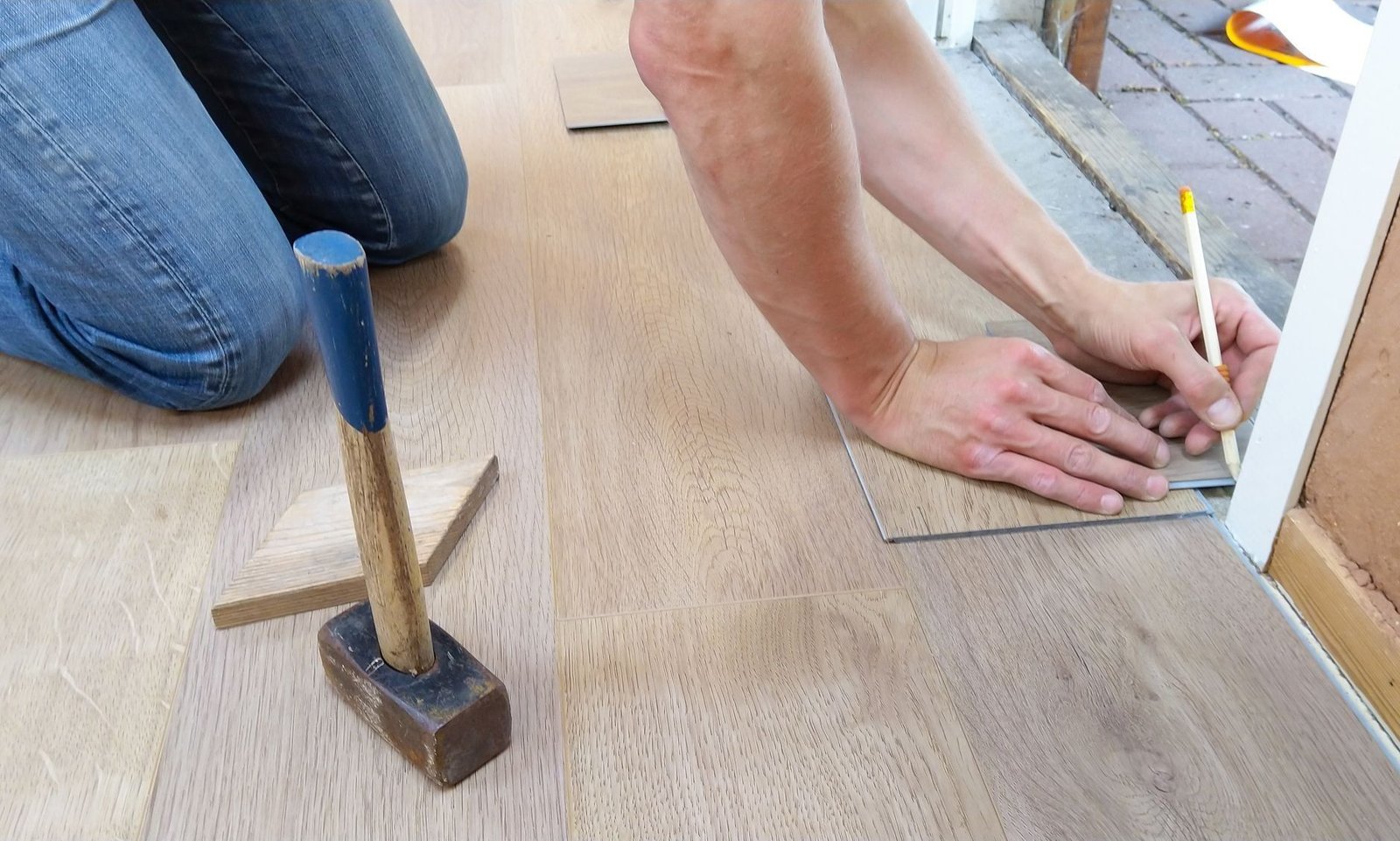 Hands measure and mark a laminate board