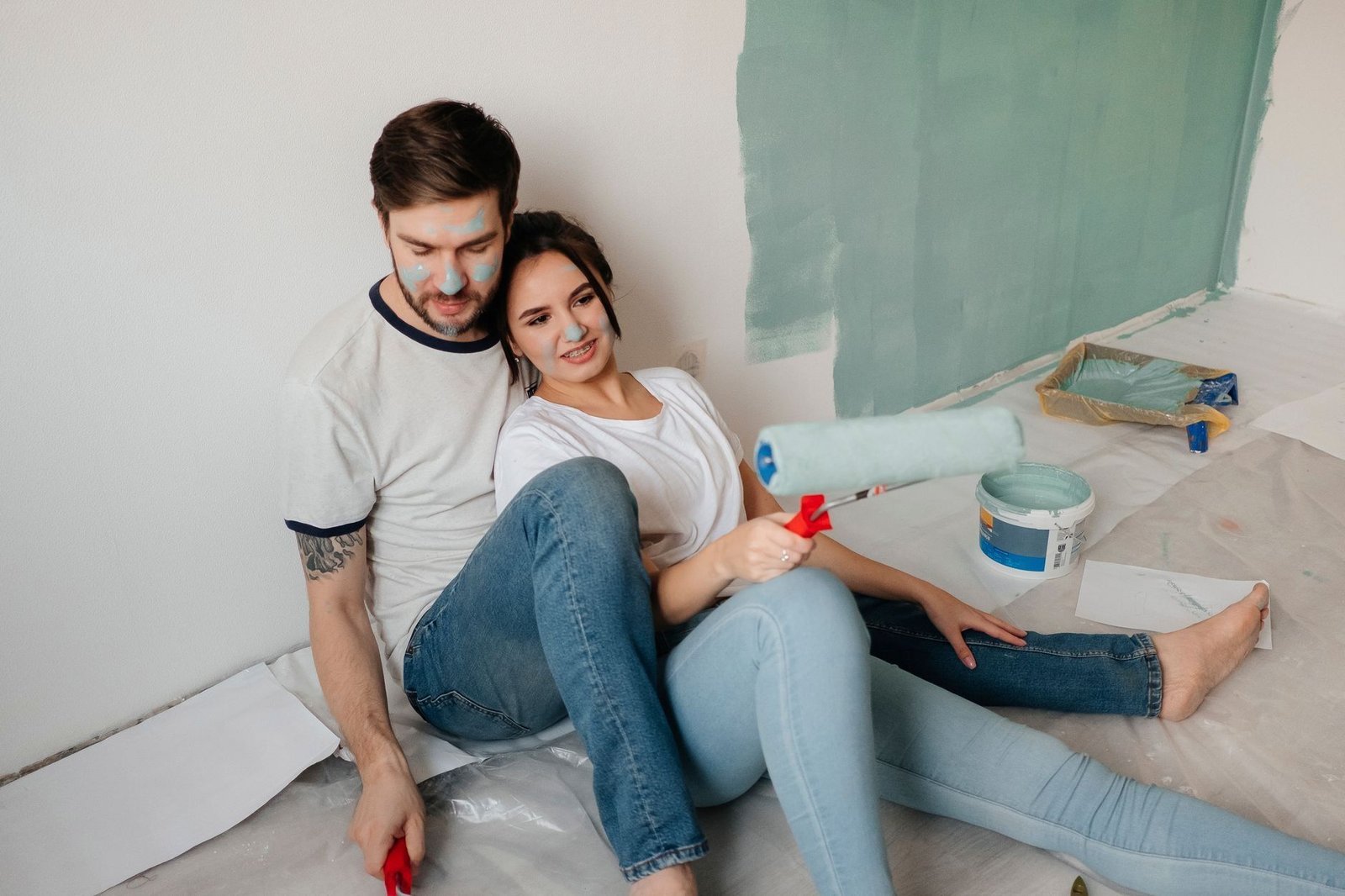 A young couple takes a break on the floor while painting walls